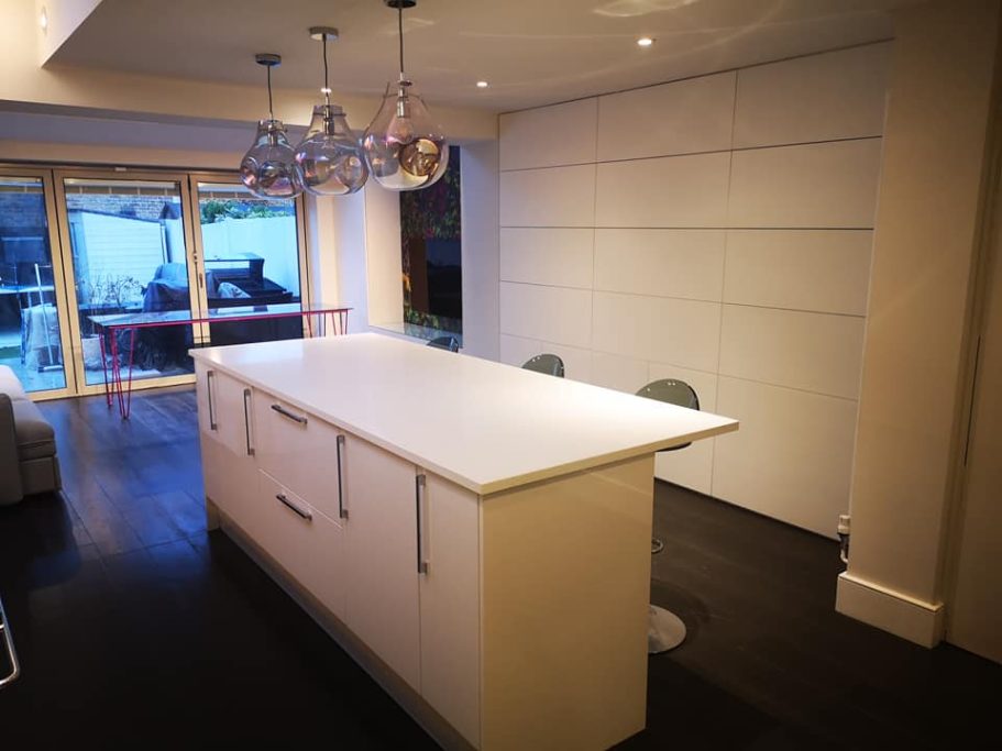 Modern kitchen with a white island unit and two stools, featuring sliding doors to the outside.